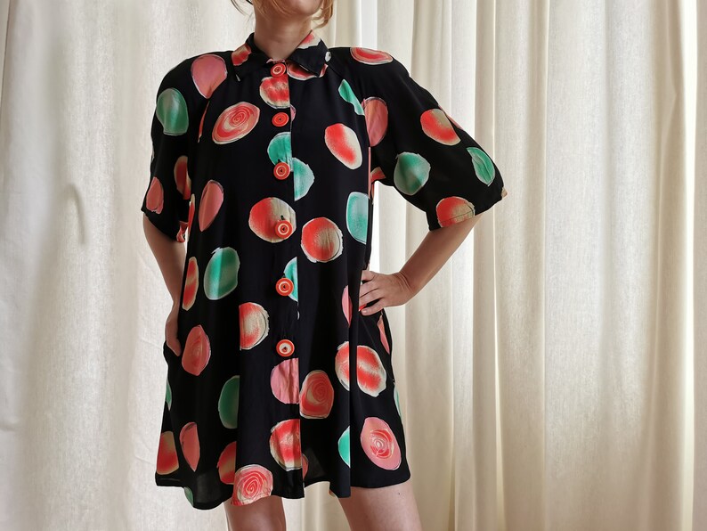 May include: A black short-sleeved button-up dress with a colorful abstract print of circles in shades of pink, green, and orange.