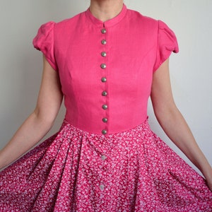 May include: A pink dress with a white floral print skirt and a solid pink bodice with a button-up front.