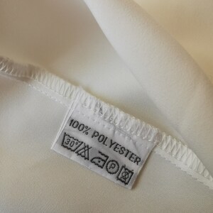 May include: White fabric label with black text that reads "100% POLYESTER" and includes care instructions symbols.