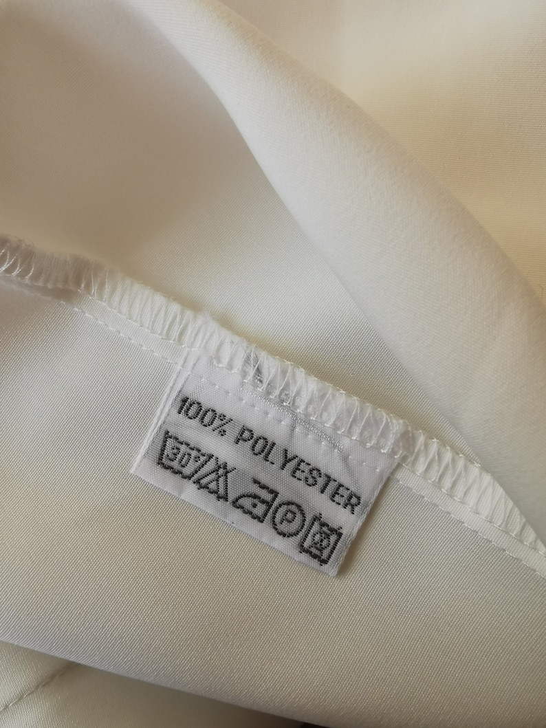 May include: White fabric label with black text that reads "100% POLYESTER" and includes care instructions symbols.