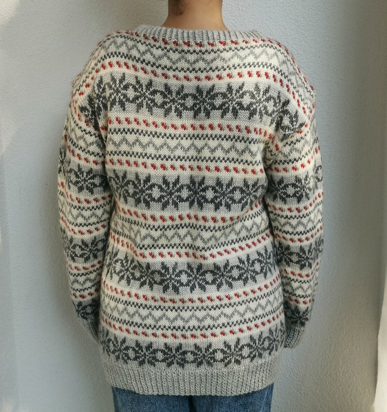 May include: A gray and white sweater with a red and gray snowflake pattern.