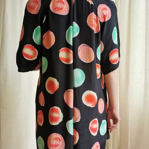 May include: A black short-sleeved dress with a large, abstract print of pink, orange, and green circles.