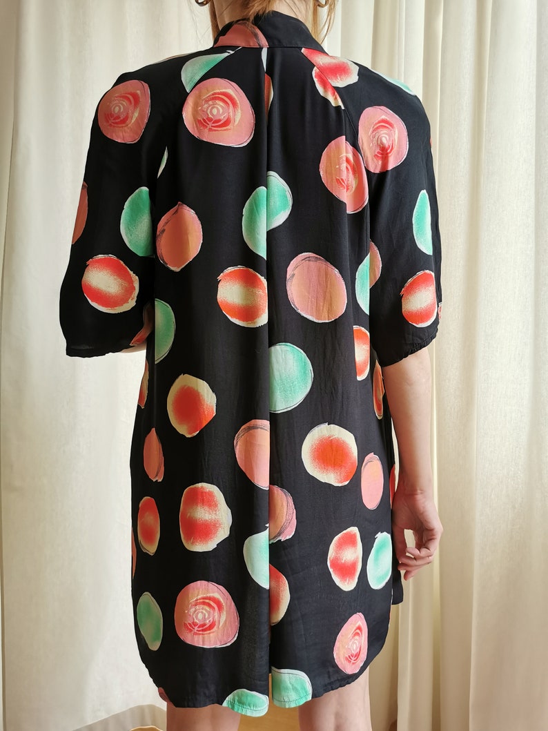 May include: A black short-sleeved dress with a large, abstract print of pink, orange, and green circles.