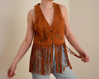 May include: A brown suede vest with fringe and beaded embellishments. The vest has a V-neck and a button closure.