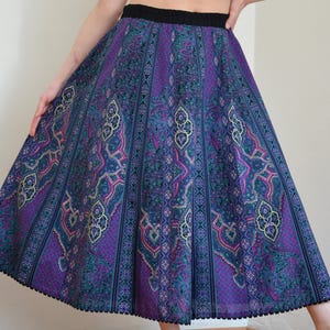 May include: A purple and blue skirt with a paisley pattern and black trim. The skirt is full and flowing.