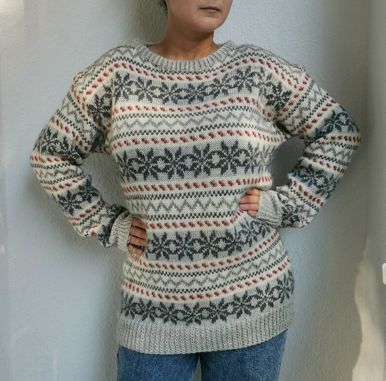 May include: A white, gray, and red patterned sweater with a crew neck.