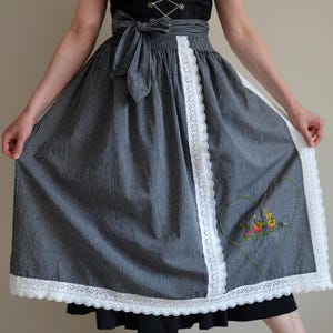 May include: A blue and white striped skirt with a white lace trim and a heart-shaped embroidered design. The skirt is a traditional style with a gathered waist and a full skirt.