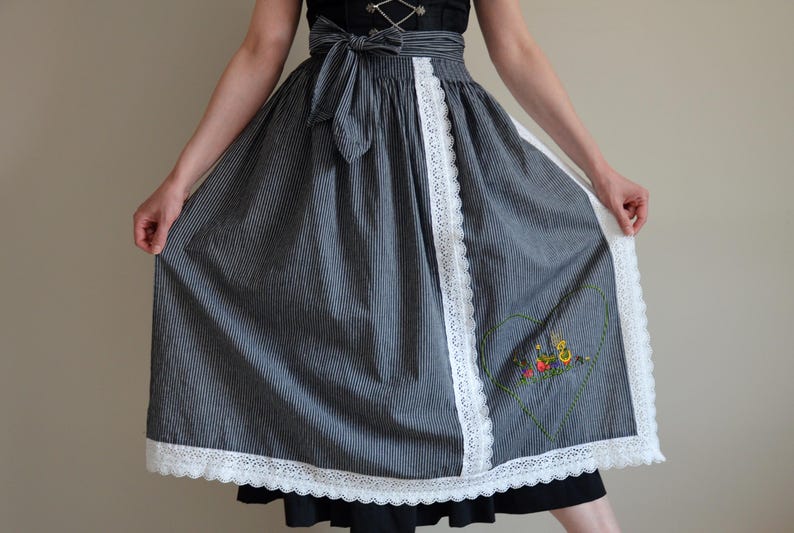 May include: A blue and white striped skirt with a white lace trim and a heart-shaped embroidered design. The skirt is a traditional style with a gathered waist and a full skirt.