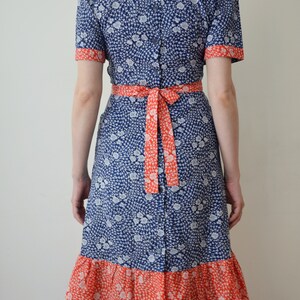 May include: A blue and red floral print dress with a ruffled hem and a tie at the waist.