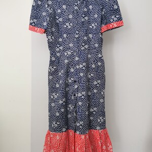 May include: A blue and white floral print dress with a red trim and a ruffled hem.