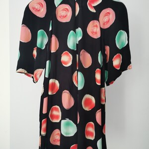 May include: Black short-sleeved blouse with a colorful abstract print of circles and roses.