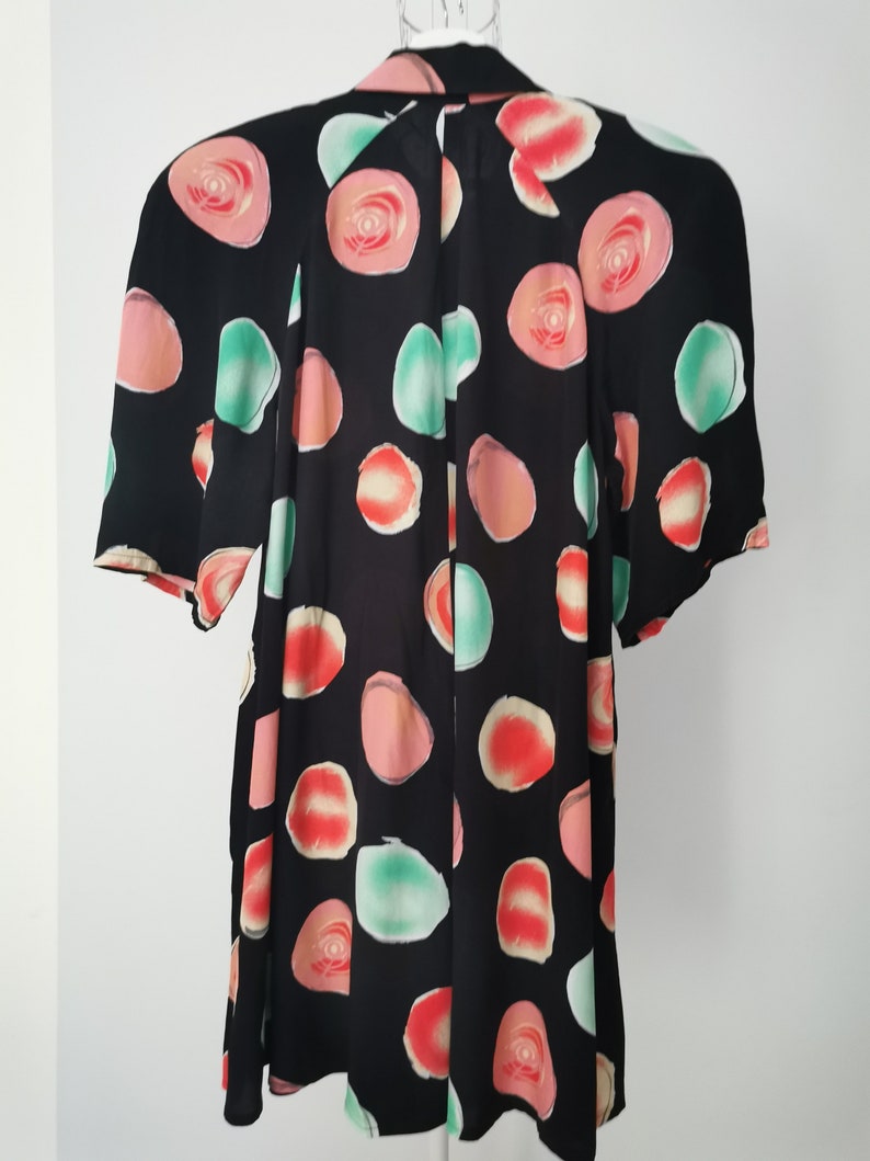 May include: Black short-sleeved blouse with a colorful abstract print of circles and roses.