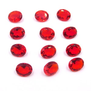 Puede incluir: Doce piedras preciosas rojas de forma ovalada dispuestas en tres filas de cuatro sobre un fondo blanco.