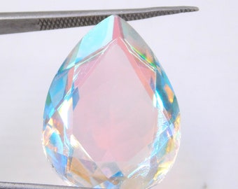 Puede incluir: Una piedra preciosa en forma de lágrima nacarada con colores arcoíris iridiscentes, sostenida por unas pinzas.