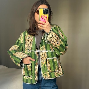 Pode incluir: Uma jaqueta acolchoada verde com estampa de tigre e fecho de botão. A jaqueta tem um bolso do lado esquerdo e um padrão de listras amarelas e marrons.