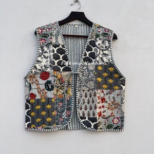 May include: A gray quilted vest with a patchwork design featuring floral and geometric patterns. The vest has a V-neck and a striped lining.