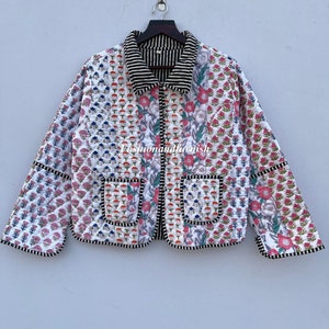 May include: A white quilted jacket with a floral print and black trim. The jacket has a collar, a button closure, and two patch pockets.