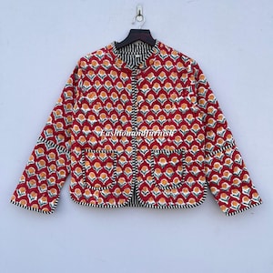 May include: A red quilted jacket with a floral print and black and white trim. The jacket has two pockets on the front and a mandarin collar.