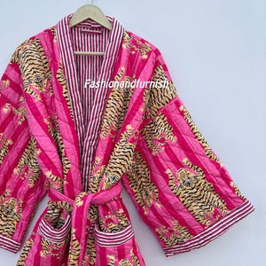 May include: A quilted pink robe with a tiger print and striped accents. The robe has a matching belt and pockets. The text "Fashionandfurnish" is visible on the front of the robe.