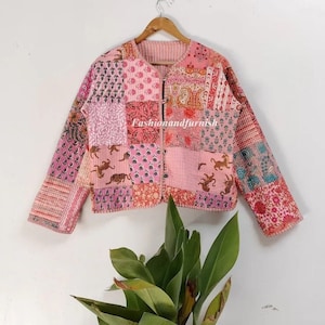Può includere: Una giacca trapuntata rosa con un design a patchwork che presenta vari motivi floreali e animali. La giacca ha una chiusura con bottoni e maniche lunghe.