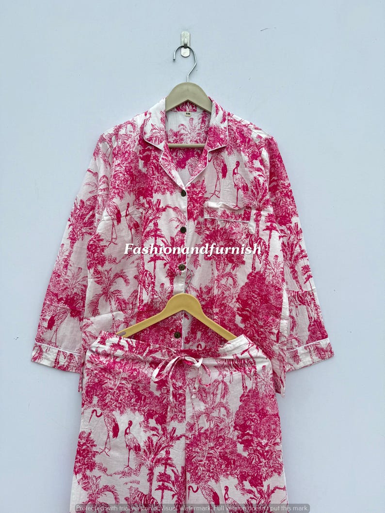 May include: A two-piece pajama set in white and pink. The set includes a long-sleeved button-down shirt and drawstring shorts. The fabric features a pink toile pattern with trees, birds, and other natural elements. The text "Fashionandfurnish" is visible.