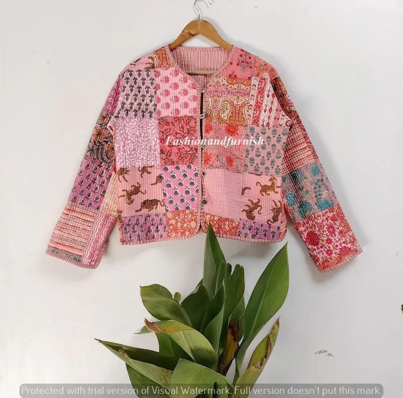 May include: A pink quilted jacket with a patchwork design featuring various floral and animal prints. The jacket has a button closure and long sleeves.