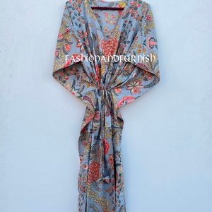 Puede incluir: Un vestido caft&aacute;n gris con estampado floral, cuello en V y cintura anudada, colgado de una percha negra. El vestido presenta dise&ntilde;os florales rojos, amarillos y rosas. El texto "FASHIONANDFURDISH" es visible.