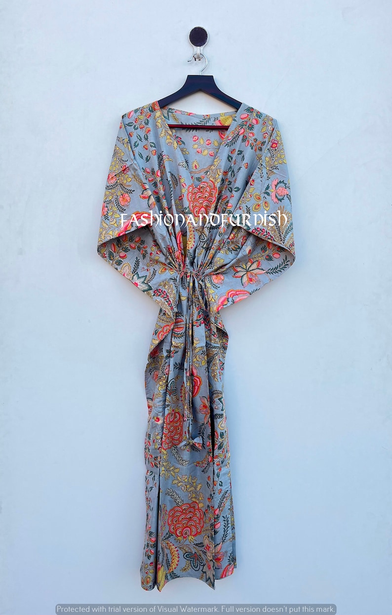 Puede incluir: Un vestido caft&aacute;n gris con estampado floral, cuello en V y cintura anudada, colgado de una percha negra. El vestido presenta dise&ntilde;os florales rojos, amarillos y rosas. El texto "FASHIONANDFURDISH" es visible.