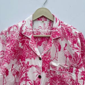 May include: White pajama top with a vibrant pink tropical print featuring flamingos, palm trees, and zebras. The top has a button-down front, a chest pocket, and white piping. The text "Fashionandfurnish" is visible on the collar.