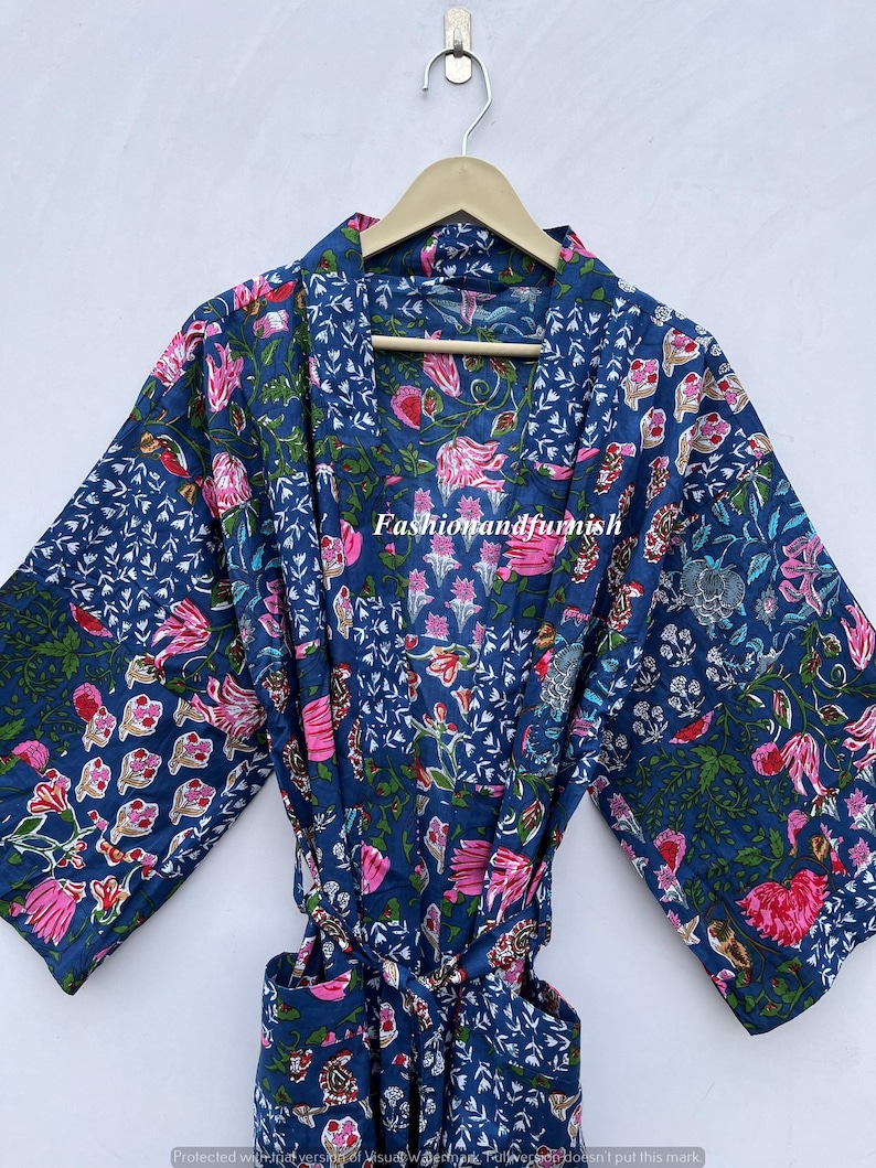 May include: A blue floral patterned robe with pink and green accents. The robe is made of a soft fabric and has a tie closure. The robe is hanging on a wooden hanger.