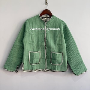 May include: A green quilted jacket with a round collar and two front pockets. The jacket has black and white striped trim along the edges, pockets, and collar. The text "Fashionandfurnish" is visible on the jacket.