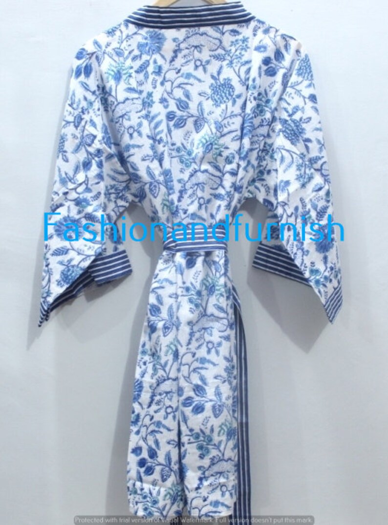 May include: A white cotton robe with a blue floral print and blue and white striped trim. The robe has a sash tie at the waist.