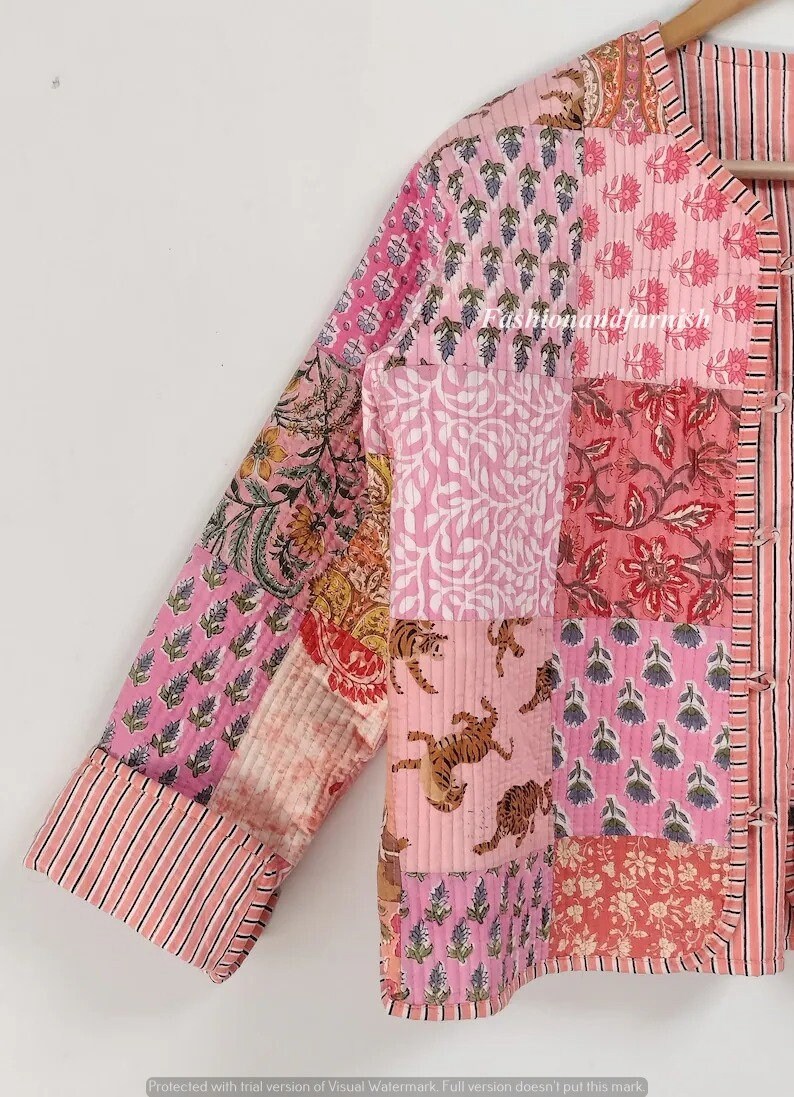 May include: A pink and white quilted jacket with a patchwork design featuring floral and tiger prints. The jacket has a mandarin collar and a button closure.