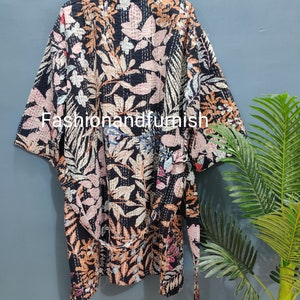 Może przedstawiać: Czarna szlafrok kimono z kwiatowym nadrukiem i paskiem do wiązania. Szlafrok ma tradycyjny japoński styl i jest wykonany z miękkiej, wygodnej tkaniny.