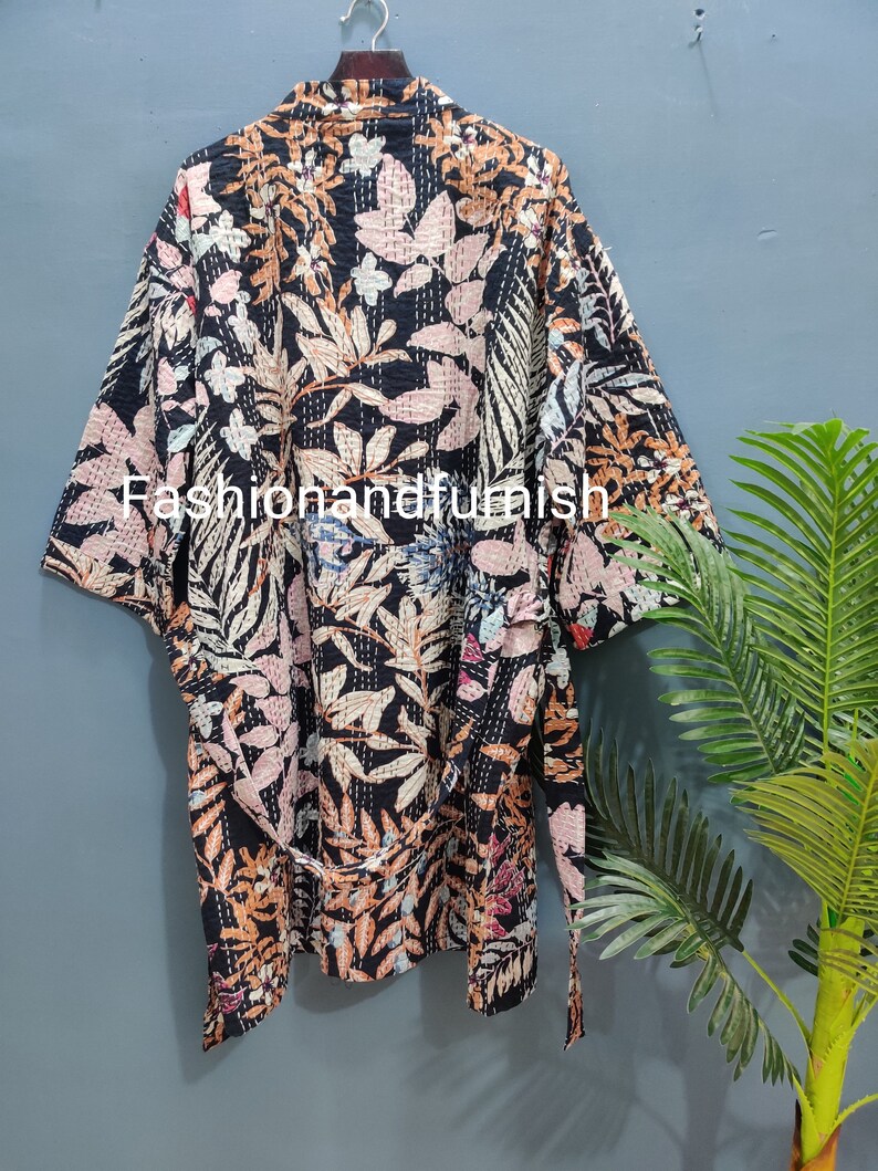Może przedstawiać: Czarna szlafrok kimono z kwiatowym nadrukiem i paskiem do wiązania. Szlafrok ma tradycyjny japoński styl i jest wykonany z miękkiej, wygodnej tkaniny.