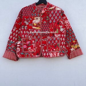 May include: A red quilted jacket with a floral and bird print. The jacket has a mandarin collar and a button closure. The fabric is quilted and has a patchwork design. The jacket has a pocket on the left side. The text "Fashionandfurnish" is printed on the front of the jacket.