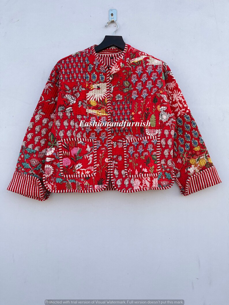 May include: A red quilted jacket with a floral and bird print. The jacket has a mandarin collar and a button closure. The fabric is quilted and has a patchwork design. The jacket has a pocket on the left side. The text "Fashionandfurnish" is printed on the front of the jacket.