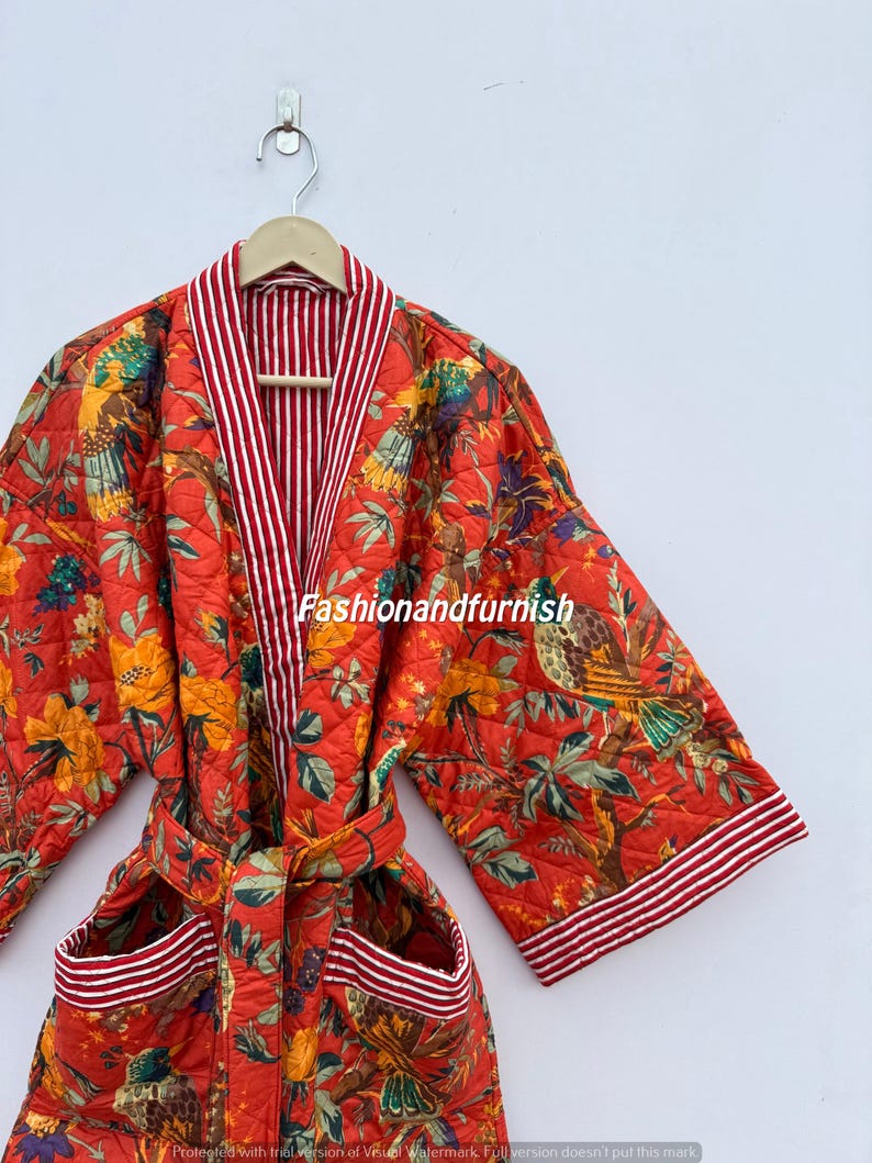 May include: A quilted red robe with a floral and bird pattern. The robe has a striped white and red trim on the collar, cuffs, and pockets. The text "Fashionandfurnish" is visible on the robe.