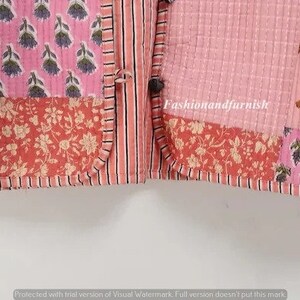 May include: A pink and red patchwork quilt with a floral and tiger print. The quilt has a button closure and is made of cotton.