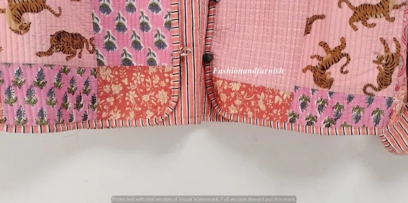 May include: A pink and red patchwork quilt with a floral and tiger print. The quilt has a button closure and is made of cotton.