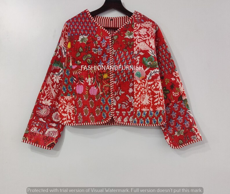 May include: A red quilted jacket with a floral print and white trim. The jacket has a button closure and long sleeves.