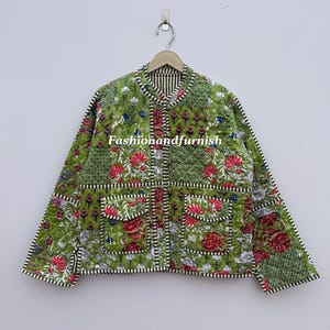 Op de afbeelding: Groene gewatteerde jas met een bloemen patchwork design, met rode en witte bloemen. De jas heeft twee voorzakken en een gestreepte kraag en bies. De tekst "Fashionandfurnish" is zichtbaar.