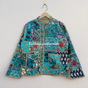 May include: A patchwork quilted jacket in teal, blue, and red floral patterns. It has a mandarin collar, two front pockets, and black and white striped trim. The text "Fashionandfurnish" is visible. The jacket is hanging on a wooden hanger.