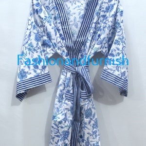 May include: A white cotton robe with a blue floral print and blue and white striped trim. The robe has a tie belt and long sleeves.