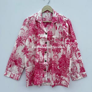 May include: White and pink pajama top with a botanical print featuring trees and birds. The long-sleeved shirt has a button-down front, a chest pocket, and white trim. The text "Fashionandfurnish" is visible.
