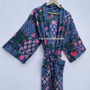 May include: A blue floral patterned robe with pink and green accents, hanging on a wooden hanger. The robe features a tie closure and pockets. The text "Fashionandfurnish" is visible on the robe.