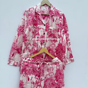 May include: A two-piece pajama set in white and fuchsia. The set includes a button-down shirt and drawstring pants, both featuring a botanical and bird print. The text "fashionandfurnish" is printed on the shirt.