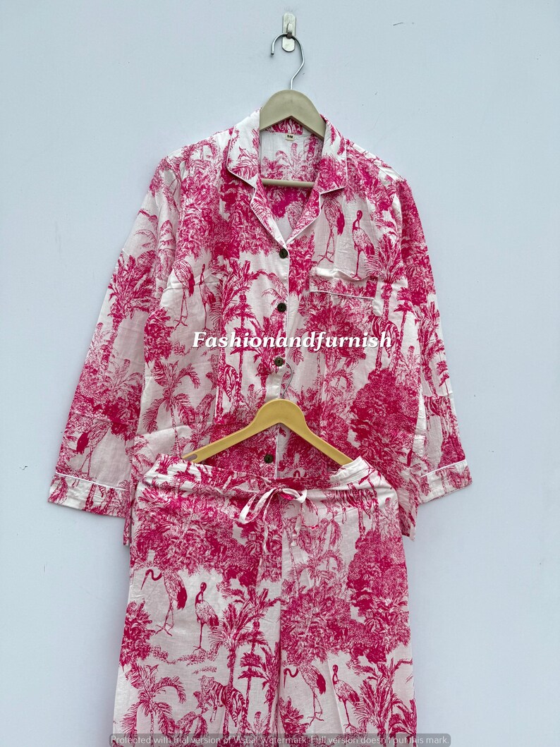 May include: A two-piece pajama set in white and fuchsia. The set includes a button-down shirt and drawstring pants, both featuring a botanical and bird print. The text "fashionandfurnish" is printed on the shirt.