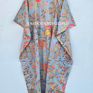 Puede incluir: Un caft&aacute;n gris con estampado floral, de dise&ntilde;o suelto y fluido. El caft&aacute;n presenta un estampado vibrante de flores y follaje rojo, amarillo y rosa. El texto "FASHIONADOFURDISH" est&aacute; impreso en la prenda.