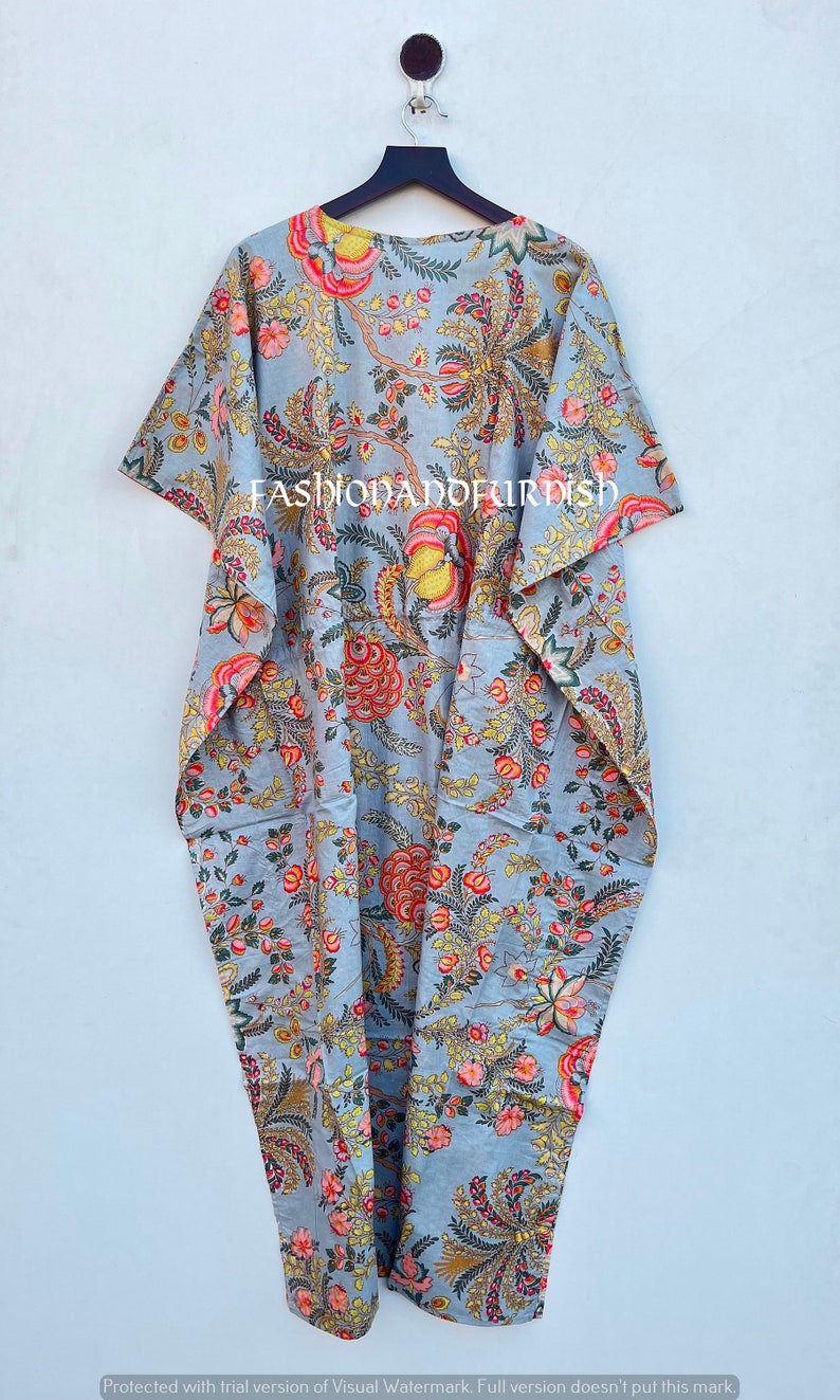 Puede incluir: Un caft&aacute;n gris con estampado floral, de dise&ntilde;o suelto y fluido. El caft&aacute;n presenta un estampado vibrante de flores y follaje rojo, amarillo y rosa. El texto "FASHIONADOFURDISH" est&aacute; impreso en la prenda.